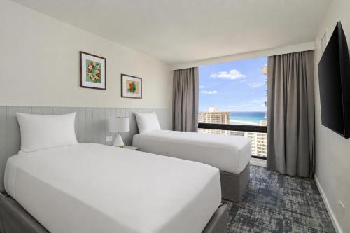 a hotel room with two beds and a large window at Aston Waikiki Sunset in Honolulu