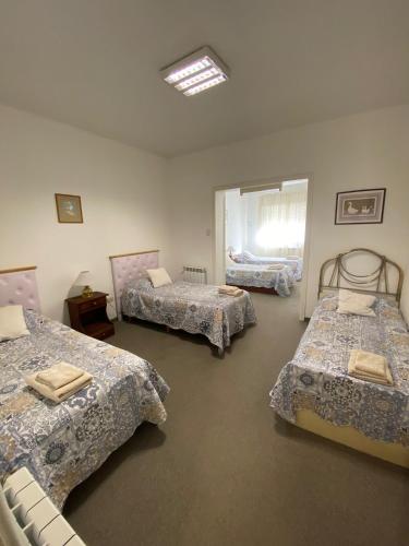 a room with three beds and a window at Espacio Patagonico in Comodoro Rivadavia