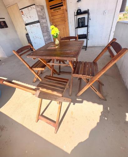 a wooden table and chairs with a vase of flowers at Por do sol residence in Aracati