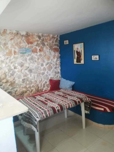 a bed in a room with a stone wall at Dari in El Haouaria