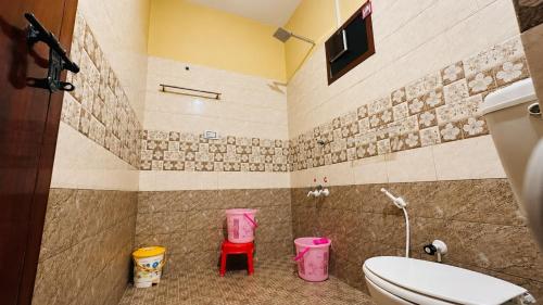 a bathroom with a toilet and two pink stools at Sahyadri Homestay wayanad in Kalpetta