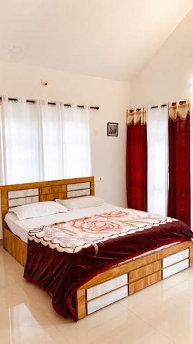 a bedroom with a large bed with red curtains at Misty Hill Land in Meppādi