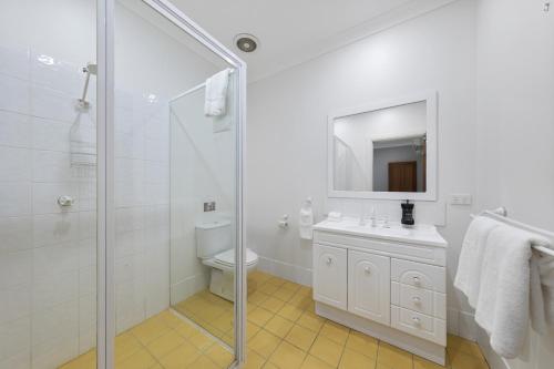 a white bathroom with a sink and a shower at Audrey Wilkinson Vineyard in Pokolbin