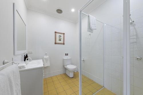 a white bathroom with a shower and a toilet at Audrey Wilkinson Vineyard in Pokolbin