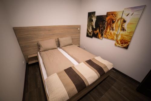 a bed in a room with two pictures on the wall at Relax Apartmanház in Mórahalom