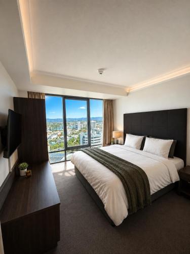 a bedroom with a large bed and a large window at Stunning City View Beachfront Apartment in Gold Coast