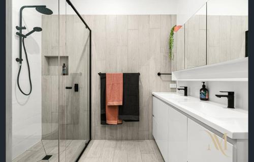 a bathroom with a shower and a sink and a mirror at Gate Access to the Beach in Edithvale