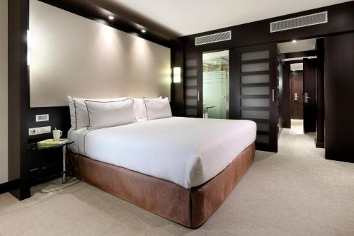 a bedroom with a large bed with white sheets at Meliá Barcelona Sarrià in Barcelona