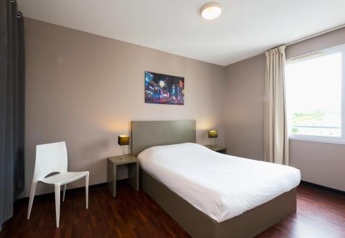 a bedroom with a large white bed and a window at Ténéo Apparthotel Talence - Centre in Talence