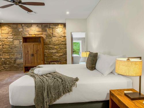 a bedroom with a large bed and a stone wall at Highwoods Cottage in Pokolbin