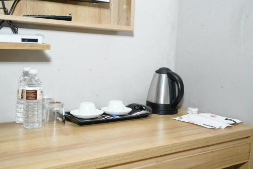 a tea kettle and cups on a wooden table at MRM Grand Park in Pudukkottai