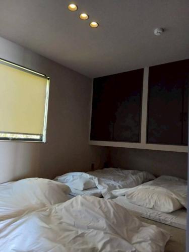 two unmade beds in a bedroom with a window at Ciel Bleu in Yamaguchi
