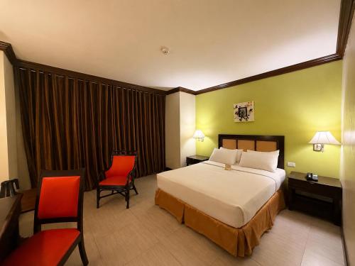 a hotel room with a bed and two chairs at The Royal Mandaya Hotel in Davao City
