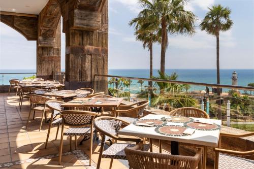 an outdoor patio with tables and chairs and the ocean at Holiday World Polynesia, Affiliated by Meliá in Benalmádena