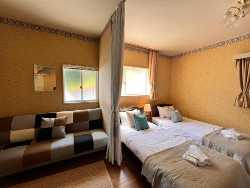 two beds in a room with a couch and a window at 伊豆ビーチクラブ in Shimoda