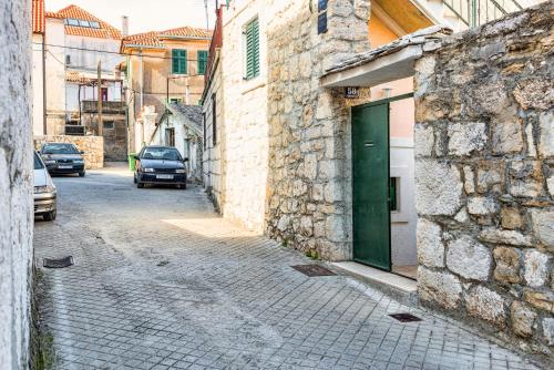 an alley with a green door on a stone building at Guesthouse F in Split