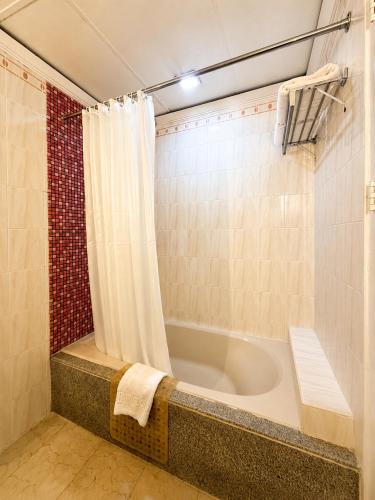a bathroom with a bath tub with a shower curtain at The Royal Mandaya Hotel in Davao City