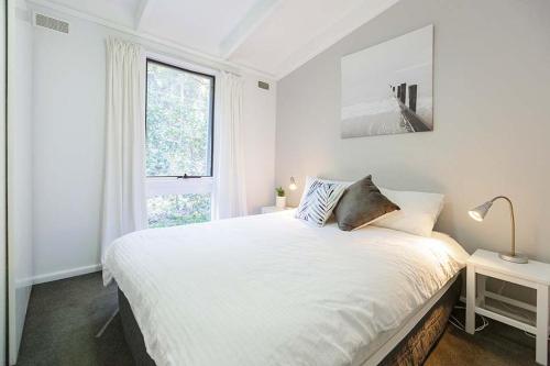 a white bedroom with a large bed and a window at Sandpiper On Smiths Lake in Smiths Lake