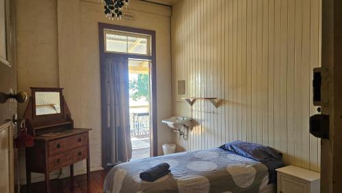 a bedroom with a bed and a mirror and a window at Hotel Shakespeare Barcaldine in Barcaldine