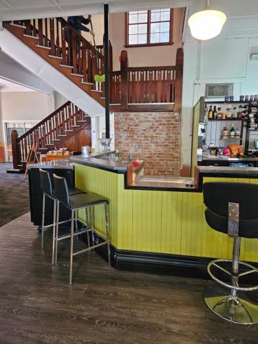 a green bar with stools in a room with stairs at Hotel Shakespeare Barcaldine in Barcaldine