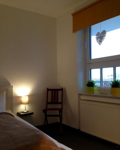 a bedroom with a bed and a window with a chair at de Rob Plat in Dorum-Neufeld