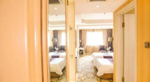 a hotel room with four beds and a mirror at Changchun Global Hotel in Changchun