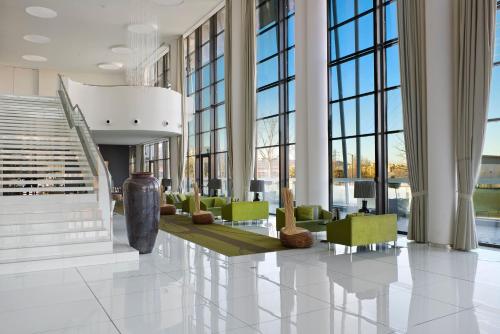 a lobby with green chairs and large windows at Meliá Braga Hotel & Spa in Braga