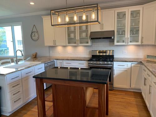 a kitchen with white cabinets and a black counter top at Tortuga home in Holden Beach