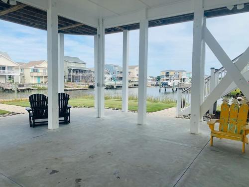 a porch with chairs and a view of the water at Shore Beats Workin' in Holden Beach