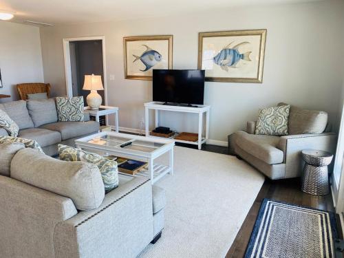 a living room with two couches and a tv at Dune Deck North - Duplex in Holden Beach