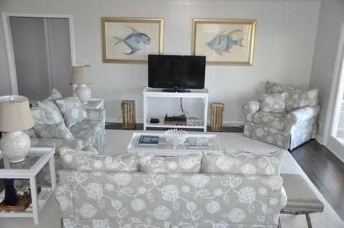 a living room with a couch and a flat screen tv at Dune Deck South - Duplex in Holden Beach