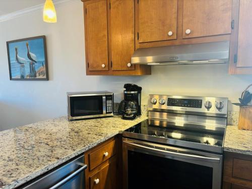a kitchen with a stove and a microwave at Plan Beach home in Holden Beach