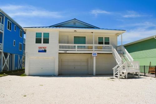 a house with two garage doors and a staircase at Do-Little Dock in Holden Beach