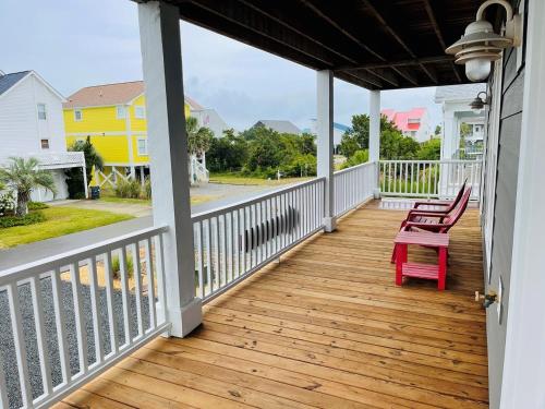 a porch with a red rocking chair on it at Compass Rose in Holden Beach