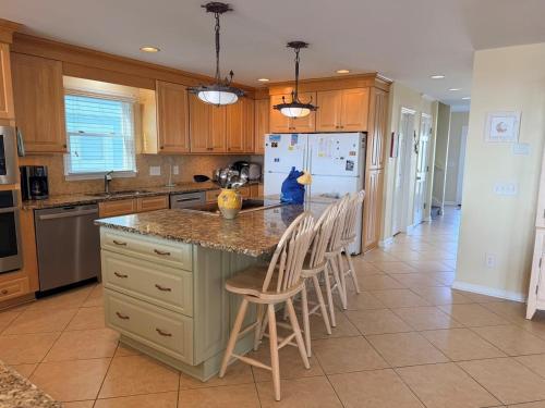 a kitchen with a island with chairs and a refrigerator at Majak Moments in Holden Beach