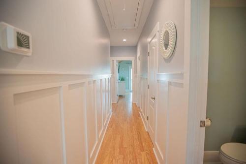 a hallway with white walls and a wooden floor at The Sandbox home in Holden Beach