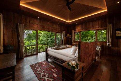 a bedroom with a bed in a room with windows at Pa Sak Tong in Chiang Rai