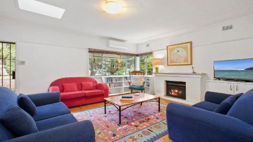 a living room with two blue couches and a fireplace at King Parrot Cottage - Close To Beach in Pearl Beach