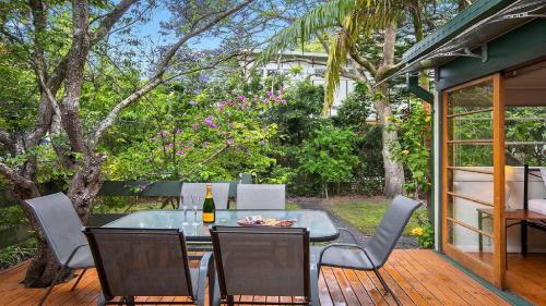 a patio with a table and chairs on a deck at King Parrot Cottage - Close To Beach in Pearl Beach