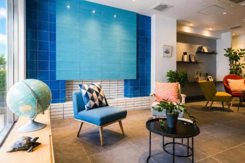 a lobby with a blue wall and chairs and a table at NAGI Hiroshima Hotel and Lounge in Hiroshima