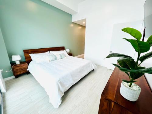 a bedroom with a white bed and a potted plant at Sleek 2BD 2BA Condo In Miami Design District in Miami