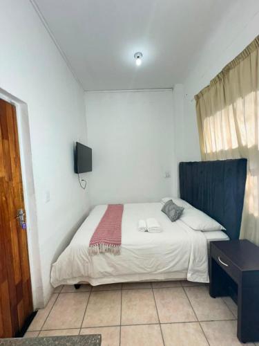 a bedroom with a bed and a tv on the wall at Airport Lodge Hotel in Kempton Park
