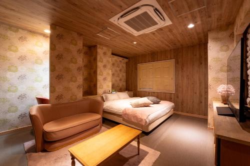 a bedroom with a bed and a couch and a chair at MONI hotel in Atsugi