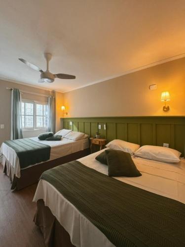 a hotel room with two beds and a ceiling fan at Pousada dos Franceses in São Paulo