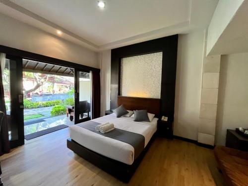 a bedroom with a large bed and a large window at Taman Agung Hotel in Sanur