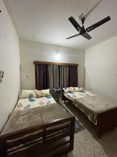 two beds in a room with a ceiling fan at Oakville in Mysore