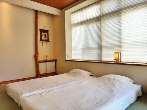 a bedroom with a bed in front of a window at Guest House Ishigaki in Ishigaki Island