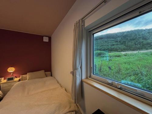 a bedroom with a window with a bed and a view at Ehana Cofee Roastery Hanare in Kami-furano