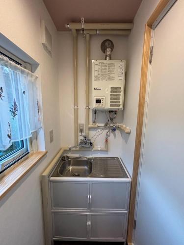 a kitchen with a sink and a microwave at Ehana Cofee Roastery Hanare in Kami-furano