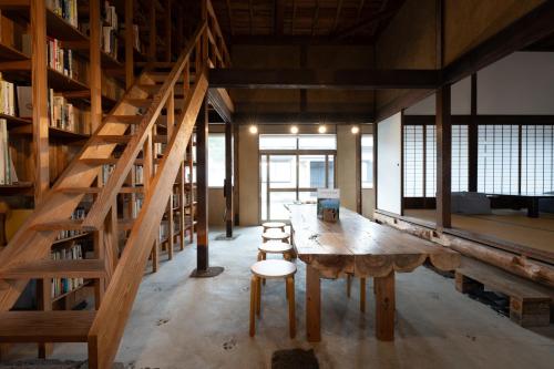 a large room with a table and chairs and bookshelves at 泊れる図書館 さんごさん in Goto